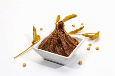 Light brown miso paste isolated on white background. Traditional Japanese seasoning, dry soya beans pods, copy space, close upの写真素材
