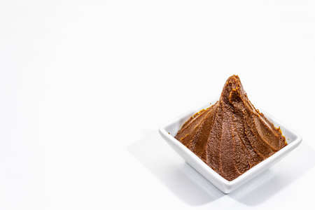 Light brown miso paste isolated on white background. Traditional Japanese seasoning, indispensable ingredient for cooking soup stock, copy space, close upの写真素材