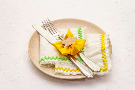 Easter table setting on textured white putty background. Spring holiday card template. Cutlery,...