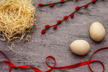 Zero waste Easter concept. Wooden egg, bird's nest, satin ribbon, red willow seals. No plastic, eco trend. Gray concrete backgroundの写真素材