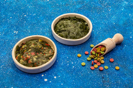 Assorted different types of food for aquarium fish. Flakes, spirulina, pills, mixture. Navy blue sea background, copy spaceの写真素材