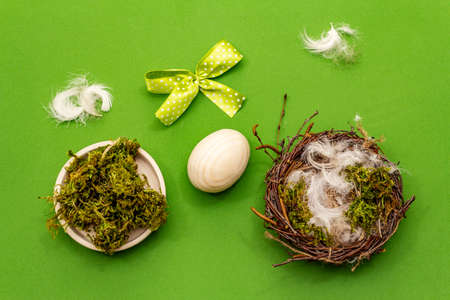 Easter zero waste decor, DIY concept. Design element and decor. Bird nest, egg, moss, bow, feather. Green background, top viewの写真素材