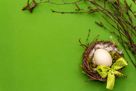 Easter zero waste decor, DIY concept. Design element and decor. Bird nest, egg, moss, birch branches, feather. Green background, top view, copy spaceの写真素材