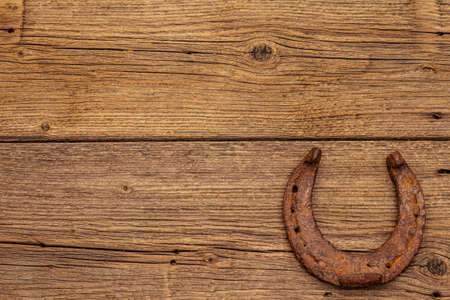 Cast iron metal horse horseshoe. Good luck symbol, St.Patrick's Day concept. Old wooden background, horse accessories, top viewの写真素材