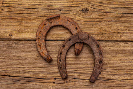 Cast iron metal horse horseshoes. Good luck symbol, St.Patrick's Day concept. Old wooden background, horse accessories, top viewの写真素材