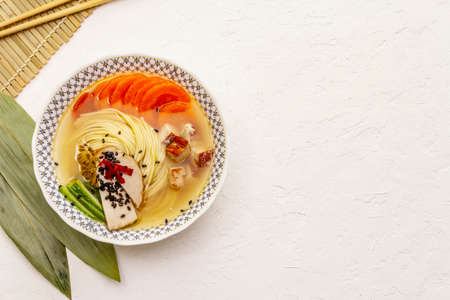 Korean noodle soup with smoked chicken and vegetables. Spring spicy dish for healthy meal. White...
