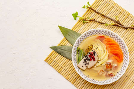 Korean noodle soup with smoked chicken and vegetables. Spring spicy dish for healthy meal. White...