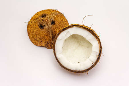 Ripe coconut cut on two half isolated on white background. Fresh fruit, ingredient for cooking food or beauty self careの写真素材
