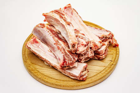 Raw pork ribs isolated on white background. Round wooden cutting boardの写真素材