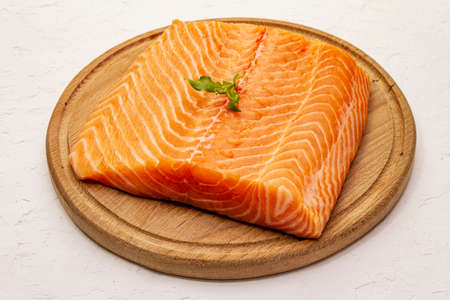 Fresh salmon filet. Wooden cutting board, concept of a healthy and balanced diet. White putty background, close upの写真素材