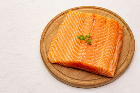 Fresh salmon filet. Wooden cutting board, concept of a healthy and balanced diet. White putty background, copy spaceの写真素材