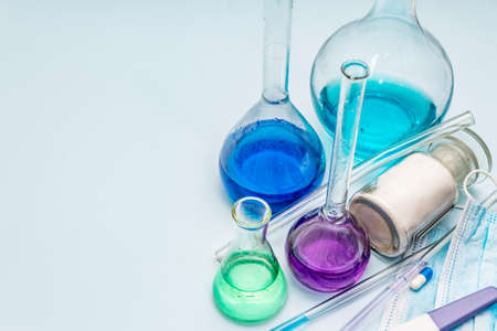Laboratory studies of coronavirus. Worldwide pandemic COVID-19, 2019-nCoV, SARS-CoV-2. Medical flasks, test tubes, antibody test, pills, powder. Light blue backgroundの写真素材