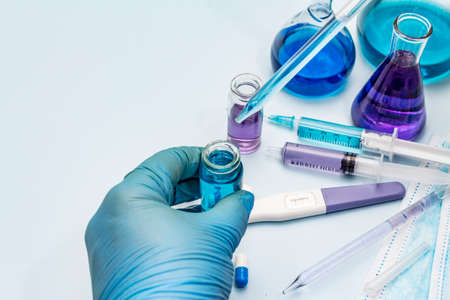 Female hand holds a test tube. Laboratory studies of coronavirus. Worldwide pandemic COVID-19, 2019-nCoV, SARS-CoV-2. Light blue backgroundの写真素材