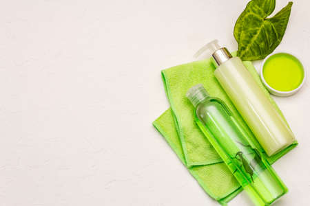 Personal care at home. Gel and tonic water with green tea, essential oil, bath towel. Natural ingredient spa concept. White putty background, top viewの写真素材