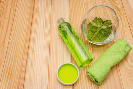 Personal care at home. Gel and tonic water with green tea, essential oil, bath towel. Natural ingredient spa concept. Wooden boards background, top viewの写真素材