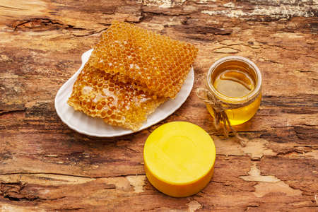 Spa concept. Self care with honey and honeycombs. Natural organic cosmetics, homemade product, alternative lifestyle. Wooden bark backgroundの写真素材