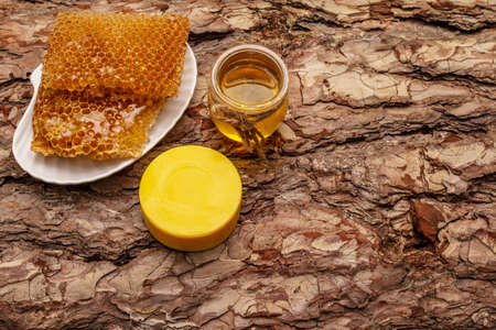 Spa concept. Self care with honey and honeycombs. Natural organic cosmetics, homemade product, alternative lifestyle. Wooden bark backgroundの写真素材