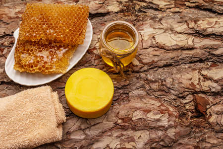 Spa concept. Self care with honey and honeycombs. Natural organic cosmetics, homemade product, alternative lifestyle. Wooden bark backgroundの写真素材