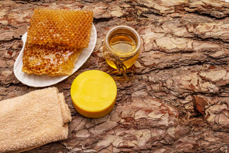 Spa concept. Self care with honey and honeycombs. Natural organic cosmetics, homemade product, alternative lifestyle. Wooden bark backgroundの写真素材