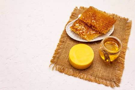 Spa concept. Self care with honey and honeycombs. Natural organic cosmetics, homemade product, alternative lifestyle. White putty backgroundの写真素材