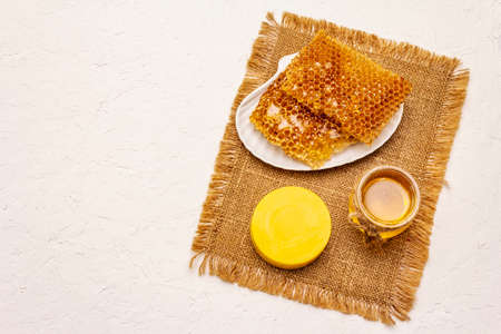 Spa concept. Self care with honey and honeycombs. Natural organic cosmetics, homemade product, alternative lifestyle. White putty backgroundの写真素材