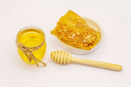 Honey, wooden honey dipper and honeycombs isolated on white background. Sweet healthy bee productsの写真素材