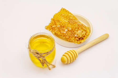 Honey, wooden honey dipper and honeycombs isolated on white background. Sweet healthy bee productsの写真素材