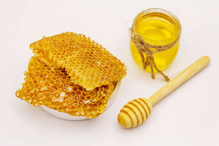 Honey, wooden honey dipper and honeycombs isolated on white background. Sweet healthy bee productsの写真素材