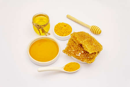 Dry turmeric powder, honey and honeycombs isolated on white background. Traditional Indian ingredient for more dishes and cosmetics, spa conceptの写真素材