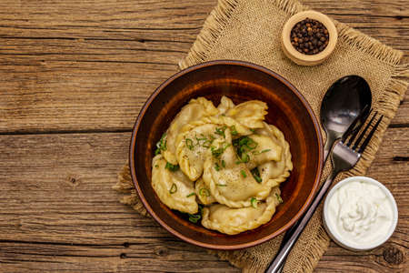 Dumplings stuffed stewed cabbage and sour cream. Traditional Ukrainian dish varenyky. Healthy vegan (vegetarian) food. Vintage wooden tableの写真素材