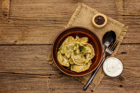 Dumplings stuffed stewed cabbage and sour cream. Traditional Ukrainian dish varenyky. Healthy vegan (vegetarian) food. Vintage wooden tableの写真素材