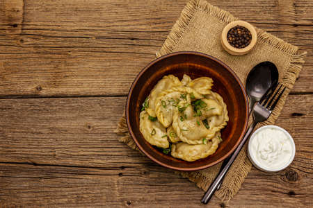 Dumplings stuffed stewed cabbage and sour cream. Traditional Ukrainian dish varenyky. Healthy vegan (vegetarian) food. Vintage wooden tableの写真素材