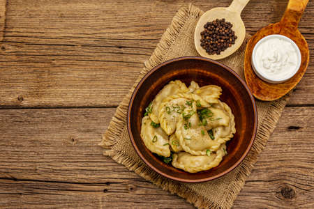 Dumplings stuffed stewed cabbage and sour cream. Traditional Ukrainian dish varenyky. Healthy vegan (vegetarian) food. Vintage wooden tableの写真素材
