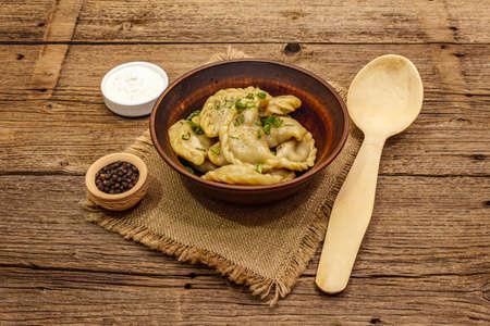 Dumplings stuffed stewed cabbage and sour cream. Traditional Ukrainian dish varenyky. Healthy vegan (vegetarian) food. Vintage wooden tableの写真素材