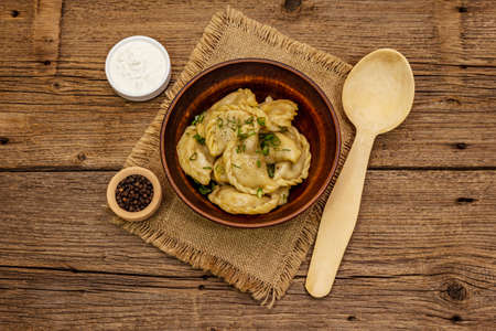 Dumplings stuffed stewed cabbage and sour cream. Traditional Ukrainian dish varenyky. Healthy vegan (vegetarian) food. Vintage wooden tableの写真素材