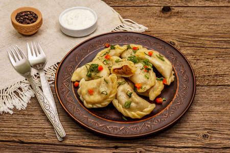 Dumplings stuffed stewed cabbage and sour cream. Traditional Ukrainian dish varenyky. Healthy vegan (vegetarian) food. Vintage wooden tableの写真素材