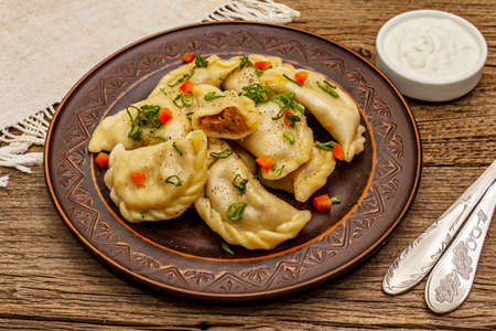 Dumplings stuffed stewed cabbage and sour cream. Traditional Ukrainian dish varenyky. Healthy vegan (vegetarian) food. Vintage wooden tableの写真素材