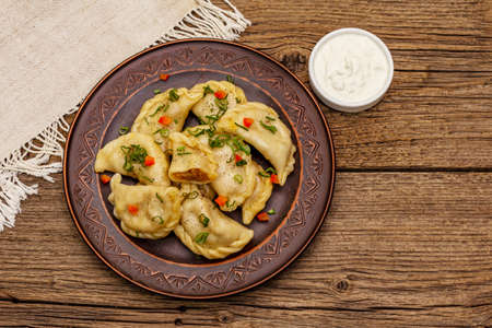 Dumplings stuffed stewed cabbage and sour cream. Traditional Ukrainian dish varenyky. Healthy vegan (vegetarian) food. Vintage wooden tableの写真素材