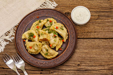 Dumplings stuffed stewed cabbage and sour cream. Traditional Ukrainian dish varenyky. Healthy vegan (vegetarian) food. Vintage wooden tableの写真素材