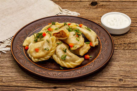 Dumplings stuffed stewed cabbage and sour cream. Traditional Ukrainian dish varenyky. Healthy vegan (vegetarian) food. Vintage wooden tableの写真素材