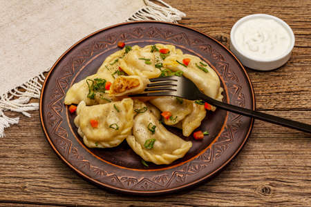 Dumplings stuffed stewed cabbage and sour cream. Traditional Ukrainian dish varenyky. Healthy vegan (vegetarian) food. Vintage wooden tableの写真素材