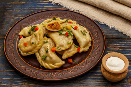 Dumplings stuffed stewed cabbage and sour cream. Traditional Ukrainian dish varenyky. Healthy vegan (vegetarian) food. Old blue wooden backgroundの写真素材