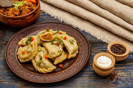 Dumplings stuffed stewed cabbage and sour cream. Traditional Ukrainian dish varenyky. Healthy vegan (vegetarian) food. Old blue wooden backgroundの写真素材