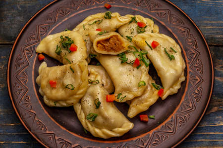 Dumplings stuffed stewed cabbage and sour cream. Traditional Ukrainian dish varenyky. Healthy vegan (vegetarian) food. Old blue wooden backgroundの写真素材