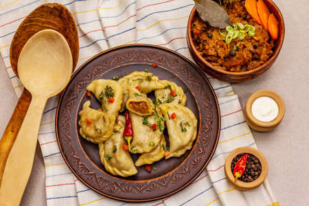 Dumplings stuffed stewed cabbage and sour cream. Traditional Ukrainian dish v-arenyky. Healthy vegan (vegetarian) food. Stone concrete backgroundの写真素材