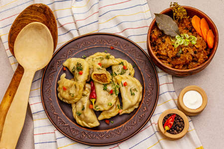 Dumplings stuffed stewed cabbage and sour cream. Traditional Ukrainian dish v-arenyky. Healthy vegan (vegetarian) food. Stone concrete backgroundの写真素材