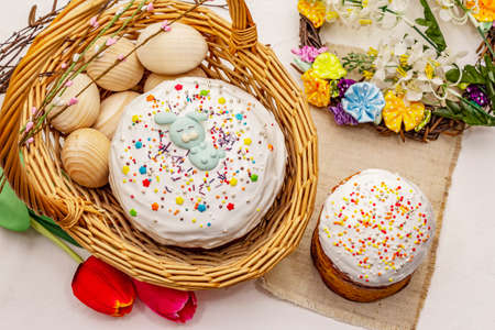 Easter cakes on white putty background. Traditional Orthodox festive bread, wicker basket and wreath, flowersの写真素材