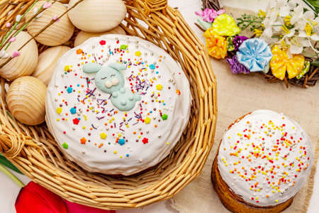 Easter cakes on white putty background. Traditional Orthodox festive bread, wicker basket and wreath, flowersの写真素材