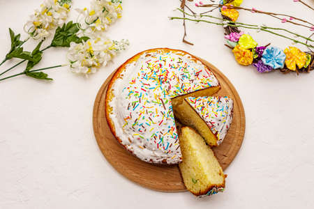 Easter cake on white putty background. Traditional Orthodox festive bread, wooden cutting board, flowers decorの写真素材
