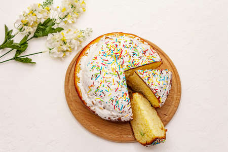 Easter cake on white putty background. Traditional Orthodox festive bread, wooden cutting board, flowers decorの写真素材